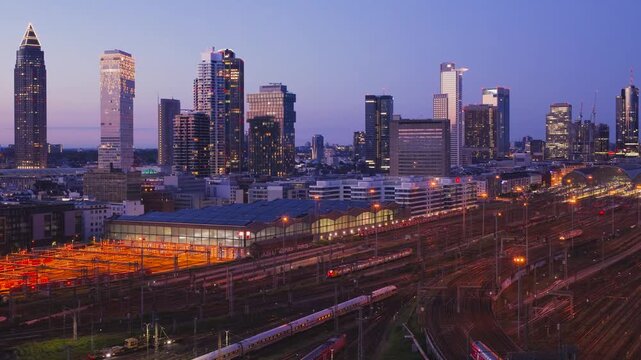Aerial view of Hauptbahnhof with illuminated skyscrapers and train tracks at twilight in Frankfurt am Main, Hessen, Germany.