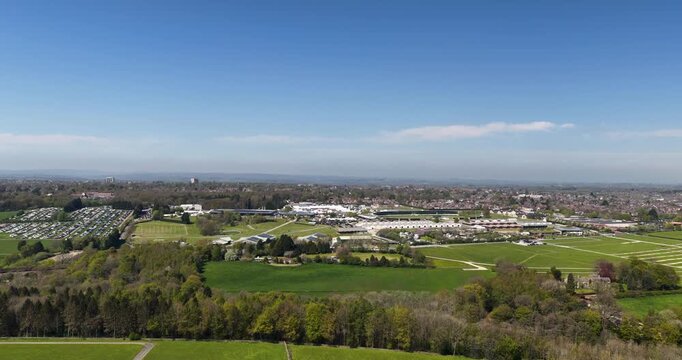 Aerial drone footage of the Harrogate Showground in North Yorkshire England with exhibition buildings parking areas countryside fields and suburban landscape beneath a blue sky with a few clouds