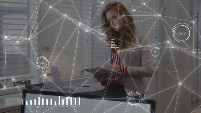 Businesswoman consulting tablet, tapping screen and analyzing HUD charts over monitor and laptop