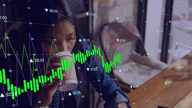 Woman sipping coffee then placing cup and starting work on laptop while finance charts overlaying