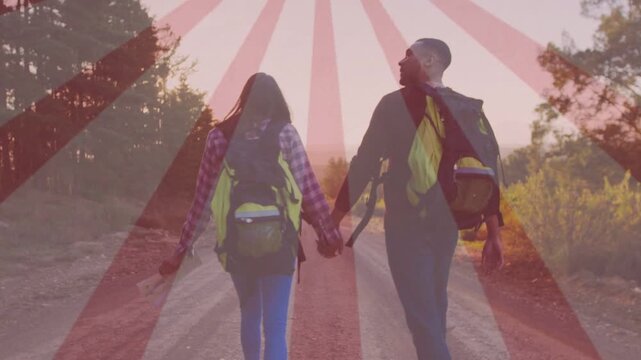 Pair walking down dirt rd to dusk holding map, packs, travel sunburst overlay appearing on horizon