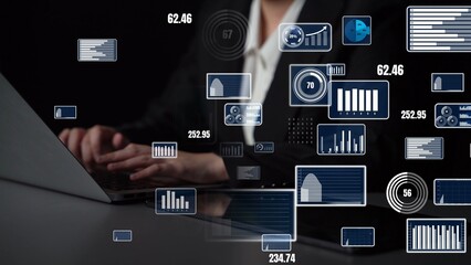 Naklejka premium A business professional works on a laptop surrounded by floating graphs and charts. The image represents modern data analysis and technology in a dark office setting. Xenic