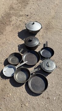 Used pans on asphalt at market sunlit cluster of assorted skillets and lids arranged for secondhand sale worn patina and rusty