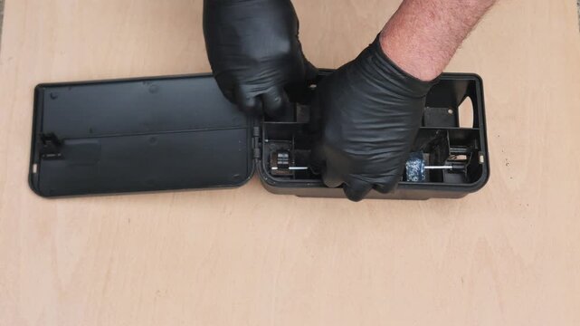 Placing blocks of rat and mice poison in a plastic bait box for pest control