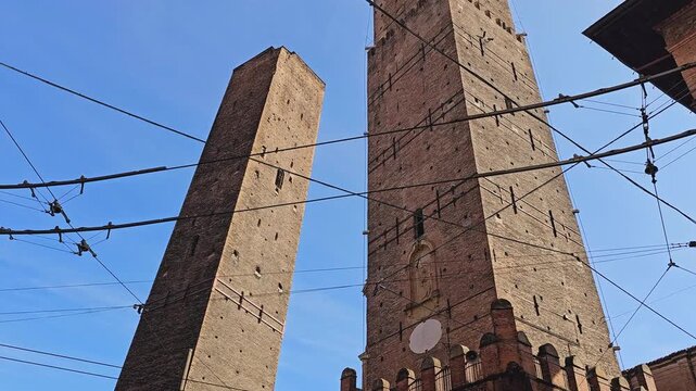 Street-level close view of the medieval Two Towers in Bologna, Emilia-Romagna, Italy, on a sunny day.