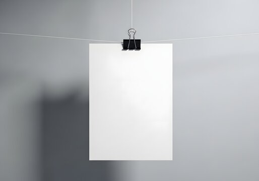 Blank white paper poster hanging on a wire with a binder clip