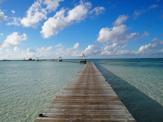 Fototapeta premium A long wooden jetty leading into the crystal-clear turquoise lagoon at Cinnamon Hakuraa Huraa, Maldives.