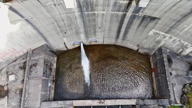 Aerial view of water discharging from a pipe into the concrete basin of the Kraftwerk Bodendorf Sperre Paal dam in Murau, Styria, Austria.