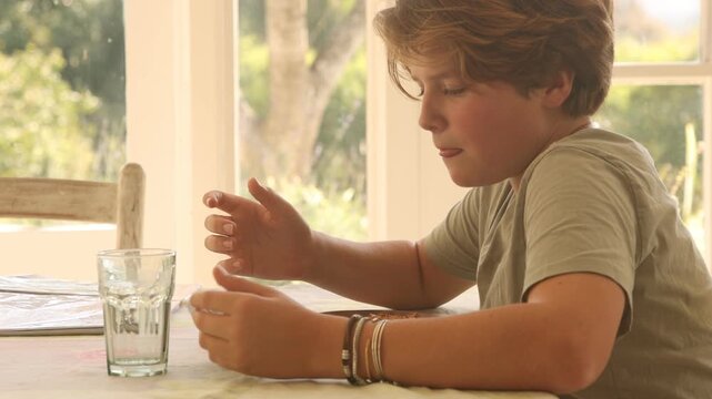 12 year old boy eating lunch and using smart phone at home