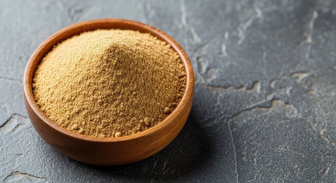A high angle cinematic macro view of fine ashwagandha herbal powder piled in a small wooden bowl on a textured stone surface for wellness, nature, earthy, holistic