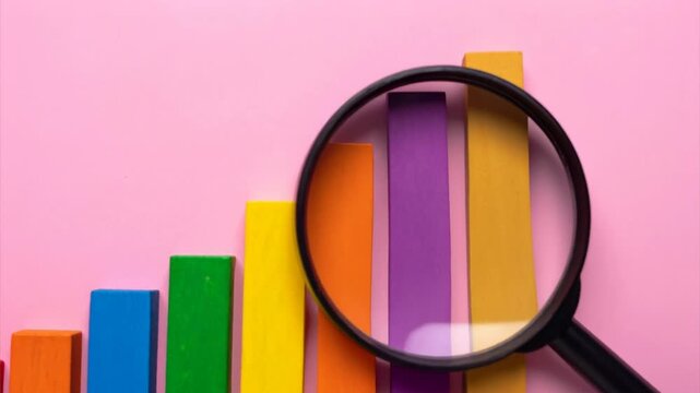 Colorful Wooden Blocks Forming Bar Graph with Magnifying Glass for Analysis and Growth Visualization in Data Representation