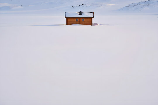 Isolated wooden cabin nestled in a vast, snow covered landscape under a clear, bright winter sky, evoking solitude and tranquility, premium commercial stock image with modern professional compos siyam