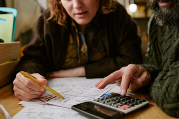 Fototapeta premium Middle aged Caucasian couple reviewing bills, calculating expenses, managing household budget and financial stress. Close up for debt, poverty, cost of living, personal finance marketing