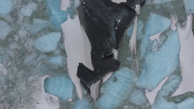 Aerial view of blue icebergs and glacial ice floating in the cold waters of the lagoon with dark volcanic sediment Fjallsarlon, Sveitarfelagid Hornafjordur, Iceland.