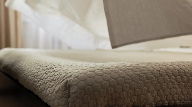 Man tosses a sheet over a double bed, like a sail, lowering it onto the mattress