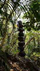 Fototapeta premium Zen rock balancing and stone stacking in a lush green forest setting.