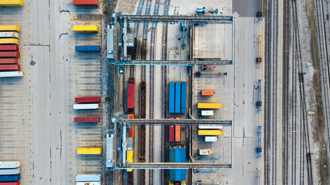 Shipping containers and railway tracks at container terminal with gantry cranes