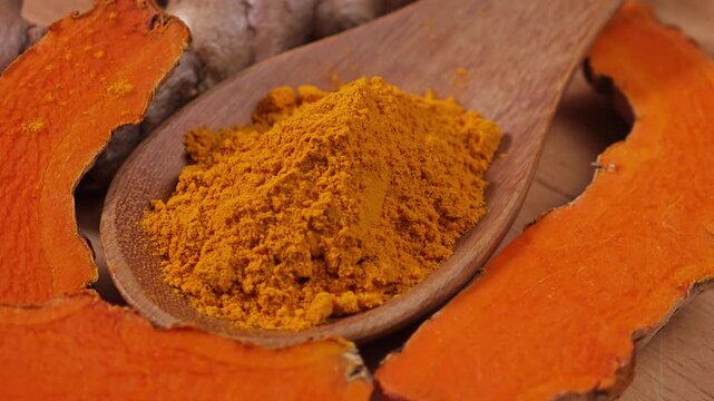 Turmeric powder and fresh turmeric on wooden background.