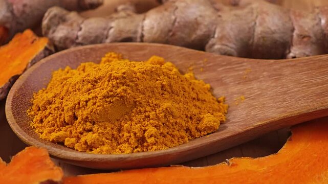 Turmeric powder and fresh turmeric on wooden background.