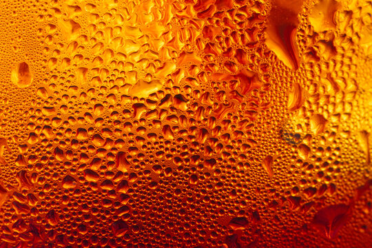 Macro shot of water droplets condensation on a cold amber beer glass texture,Close-up macro photography of refreshing cold drink background with heavy water condensation and sweat droplets on a golden