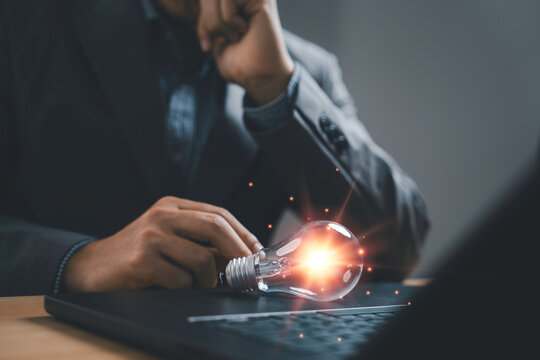 Business professional thinking with glowing light bulb on laptop, symbolizing innovation, creative problem solving and smart business ideas for startup, technology and strategy concepts.