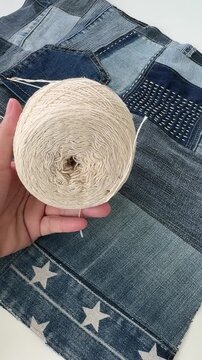 Hand Holding Cotton Yarn Ball on Handmade Denim Patchwork Fabric