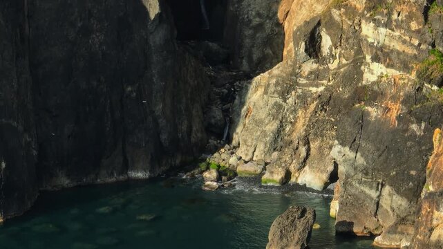 Majestic Golden Hour Light Bathes Towering Volcanic Cliffs and a Secluded Rocky Cove, Exuding a Powerful and Moody Coastal Energy on Flores Island