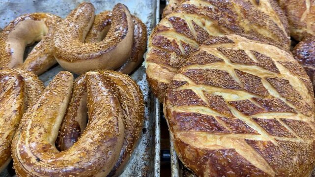 Freshly baked Turkish bagels with sesame seeds on trays in a bakery, perfect for background