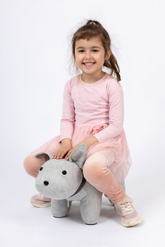 Smiling Little Girl Sitting on Plush Dog Toy Chair, Happy Child Portrait, Playful Childhood and Studio Lifestyle Concept