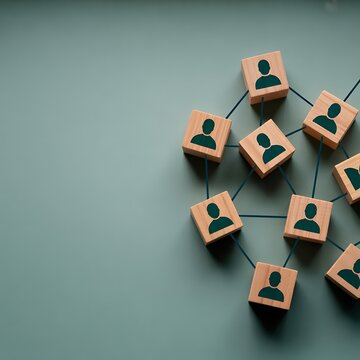 A group of wooden blocks with people icons connected by lines on a green background representing social network and communication concept