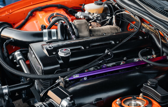 Engine bay of Toyota Supra A80 with 2JZ GTE engine. Tuned motor with black cylinder head and intake piping under the hood of an orange Toyota Supra mk4. Kyiv, Ukraine - May 16 2026