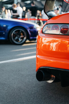 JDM car meet - Japanese cars owners gathering - rear left part of orange Toyota Supra A80 and front side part of purple Nissan Skyline R34 GT-R in the background. Kyiv, Ukraine - May 16 2026