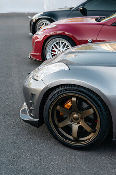 Close-up of a row of Nissan Z sports cars in parking lot. High-angle view of a grey Nissan 350Z with bronze wheels, and two custom Nissan 370Z coupes parked in a line. Kyiv, Ukraine - May 16 2026