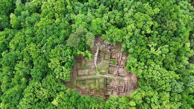 Aerial view of the ancient stone foundations of Castro de Armea archaeological site surrounded by dense green forest in Allariz, Province of Ourense, Spain.
