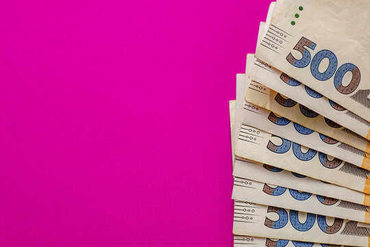 A thick stack of Ukrainian five hundred hryvnia banknotes is neatly arranged in a fan shape on the right side of the frame.