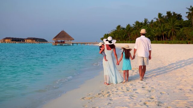A beautiful vacations family walks on a tropical paradise beach in the Maldives islands during sunset time