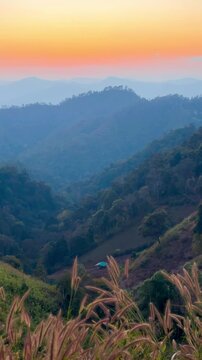 A mountain view at sunset with a soft orange sky in Thailand.