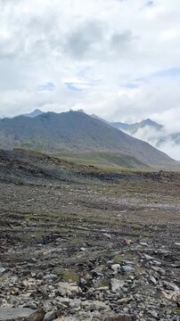 Panning view of the rocky slope in the Tianshan Mountains, Xinjiang, China. It's a rainy day with a cloudy sky. There are many rocks along the way. The idea for nature footage.
