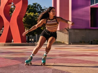 Obraz premium A woman roller skating outdoors in colorful attire during daytime, with dynamic movement and a modern urban backdrop.
