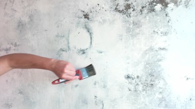 Person priming interior wall with roller in living room