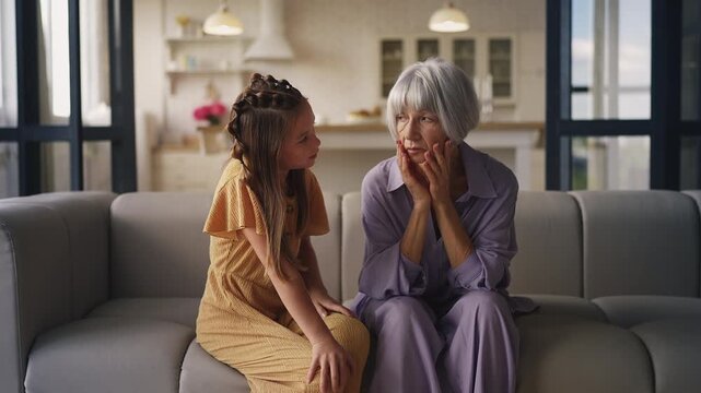 Girl comforting and hugging sad grandma, supportive family relationship