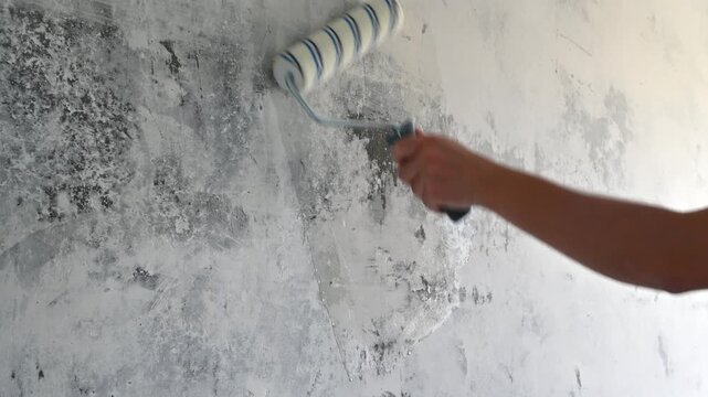 Hand rolling primer over textured interior wall to cover stains and patch