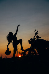 Fototapeta premium Silhouette of Woman with Motorcycle at Sunset Sky