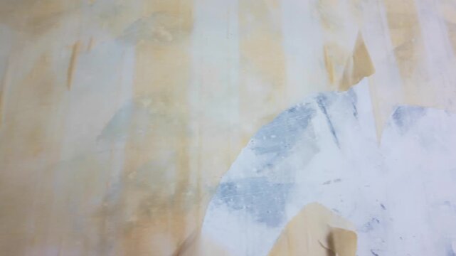 Hand peeling wallpaper from painted wall during indoor room renovation