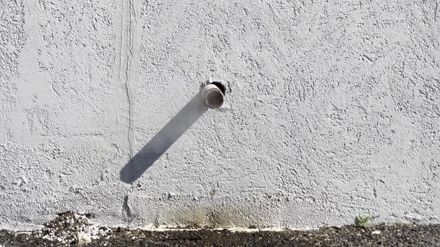 a small pipe sticking out of a wall venting steam and condensate