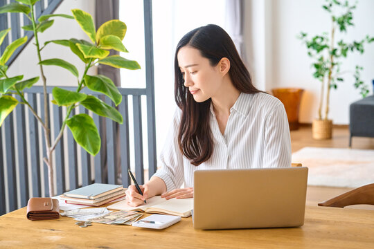 パソコンを開き家計簿を書き込む女性