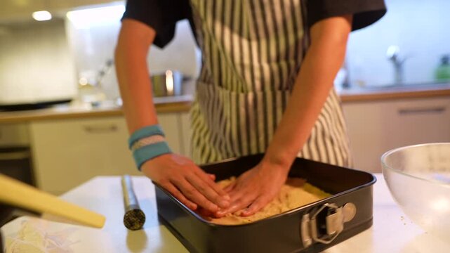 Person firmly presses crust into springform while preparing baking base