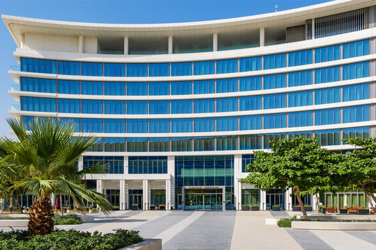 Abu Dhabi, UAE - 17 May 2026. Exterior view of The WB Abu Dhabi hotel on Yas Island featuring modern curved architecture, blue glass facade and landscaped entrance area