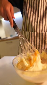 Closeup shot of yolk blending into whipped cream with rhythmic whisking