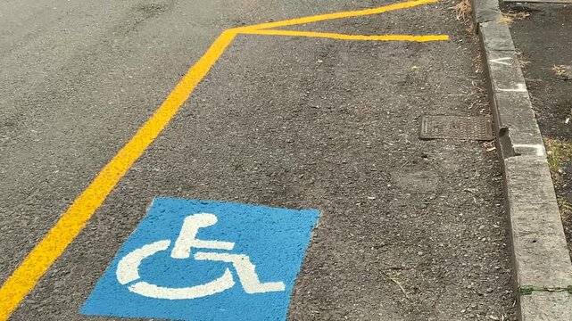 Parking space reserved for disability, marked by the traditional yellow lines and  blue international symbol featuring white wheelchair